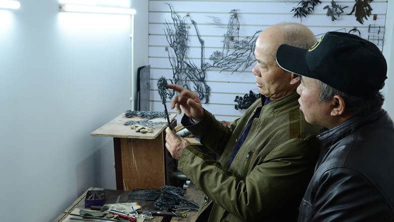 鐵畫(huà)大師張家康與徒弟魏民春探討學(xué)習(xí)迎客松制作要領(lǐng)